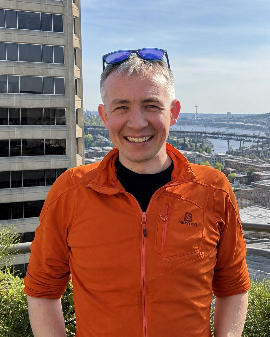 Jeffrey J. Early smiling outdoors in an orange jacket.